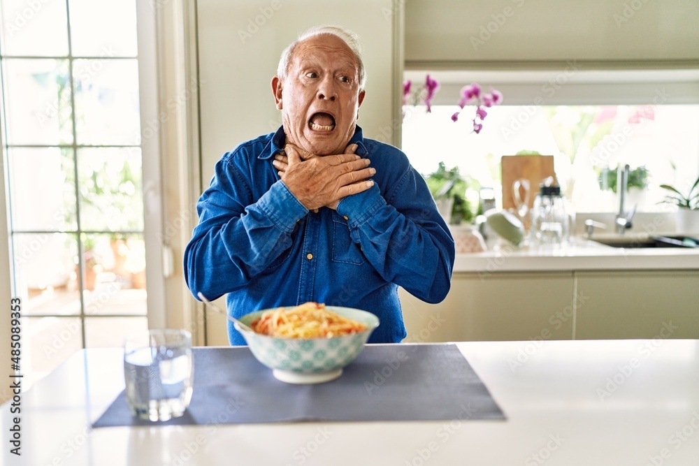 Sticker Senior man with grey hair eating pasta spaghetti at home shouting and suffocate because painful strangle. health problem. asphyxiate and suicide concept.