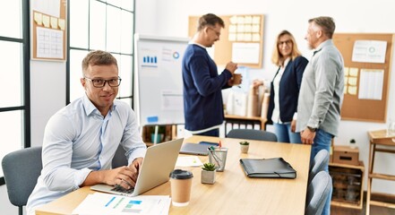 Middle age business worker smiling happy working while partners have break time at the office.