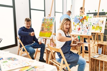 Group of middle age artist at art studio looking at the watch time worried, afraid of getting late