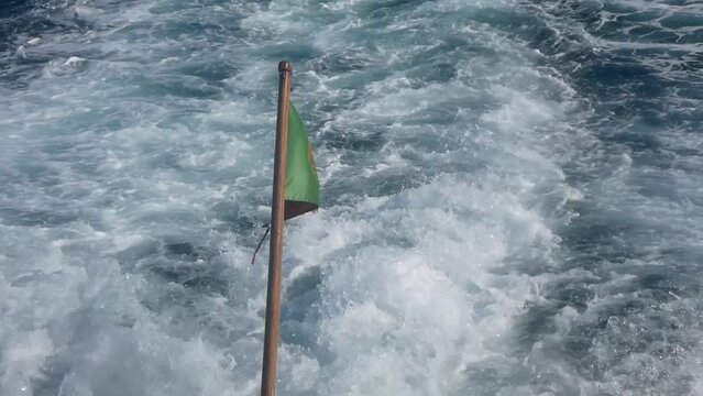Portuguese Waving Flag in the stern of a ship. View from a boart, Azores