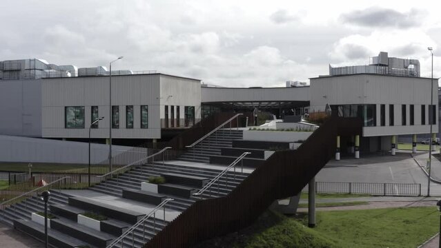 Comfortable empty stairs to footbridge with flowerbeds and railings over road near large shopping center aerial view