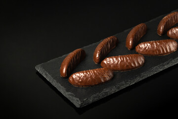 Sweets or candies on a black serving board. Assorted chocolate on a black isolated background