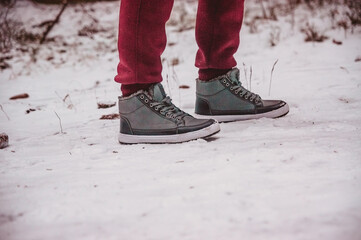 two legs in boots stand on a path in the snow in winter