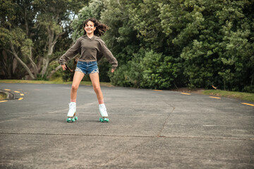 portrait of young child or teen girl roller skating outdoors, firness, wellbeing, active healthy lifestyle