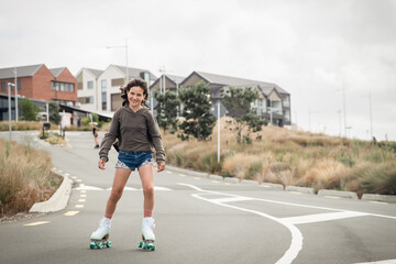 portrait of young child or teen girl roller skating outdoors, firness, wellbeing, active healthy lifestyle