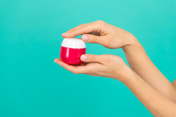 female hands hold skin cream on blue background. beauty product