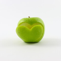 Fresh green apple with a symbol of a cut heart on the front, isolated on a white background