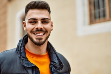Obraz premium Handsome hispanic man with beard smiling happy and confident at the city wearing winter coat