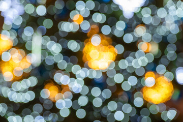 blurred lights in the background. Multicolored bokeh creating a Christmas atmosphere. Blurred christmas tree decorated with christmas lights.