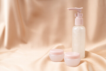 Obraz na płótnie Canvas Moisturizing anti-aging face cream on a nude pink silk fabric. Skin care.