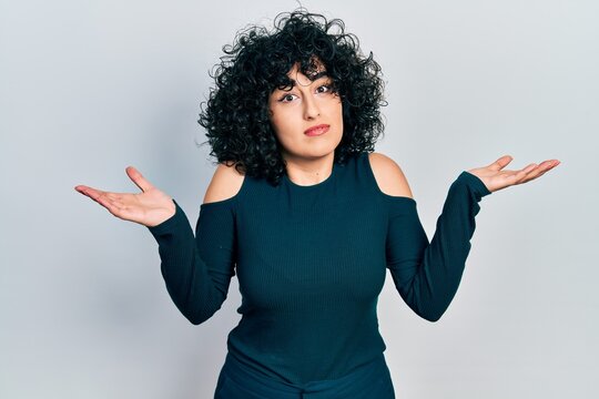Young middle east woman wearing casual clothes clueless and confused with open arms, no idea and doubtful face.
