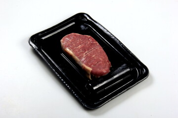 Raw New York strip steak  in black vacuum package, isolated on white background, top view