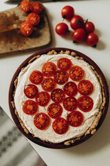 raw quiche with sliced cherry tomatoes top view. quiche with tomatoes before baking. cottage cheese pie with tomatoes and spices on top.