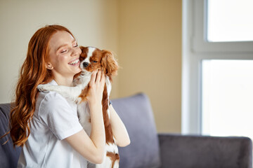 Attractive Female In Casual Wear Loving Stroking Playing With Pet Dog At Home, Charles King Spaniel...