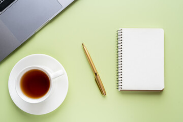 Flat lay, top view office table desk. Workspace with notebook, office supplies, pen and coffee cup with copy space on light green background.