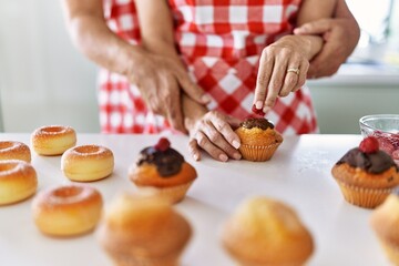 Couple cooking muffins at the kitchen.