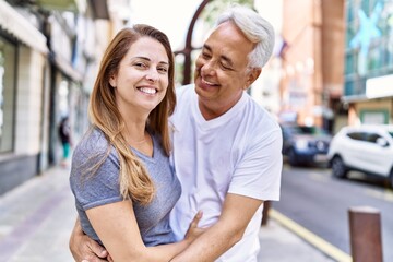 Obraz premium Middle age hispanic couple of husband and wife together on a sunny day outdoors. Smiling happy in love hugging at the city