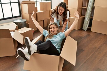 Young couple smiling happy playing using cardboard box as a car at new home.