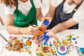 Two middle age student smiling happy painting hands at art studio.