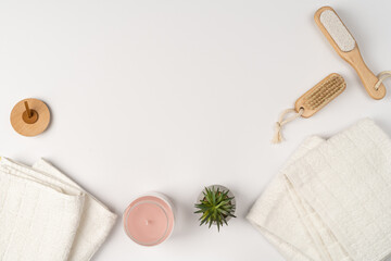 Flat lay, modern bathroom decor. Towels, wooden eco-friendly brushes and a candle in a glass jar on a white background.