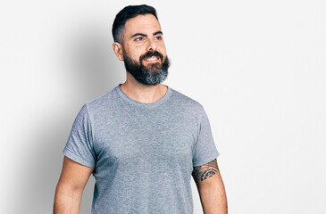 Hispanic man with beard wearing casual grey t shirt looking to side, relax profile pose with natural face and confident smile.
