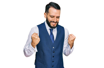 Young man with beard wearing business vest very happy and excited doing winner gesture with arms raised, smiling and screaming for success. celebration concept.