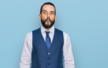 Young man with beard wearing business vest making fish face with lips, crazy and comical gesture. funny expression.