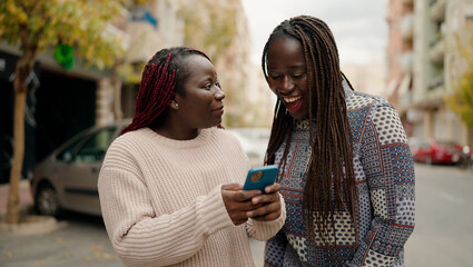 Two african american friends smiling confident using smartphone at street