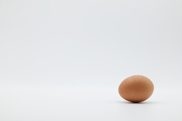 A brown egg placed horizontally on a plain white background.