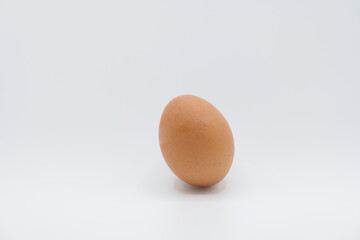 A brown egg placed tilted against a plain white background.