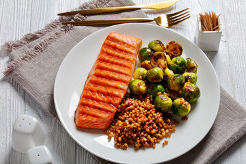 grilled salmon, brussel sprouts, spelt on a plate