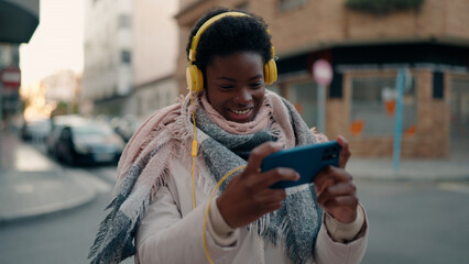Young african american woman smiling confident playing video game at street © Krakenimages.com