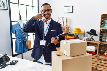African american man working as manager at retail boutique pointing with hand finger to face and nose, smiling cheerful. beauty concept