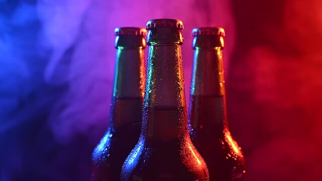 Three bottles of beer spinning in blue pink fog.
