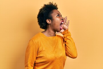 Fototapeta na wymiar Young african american woman wearing casual clothes shouting and screaming loud to side with hand on mouth. communication concept.