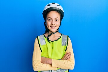 Beautiful brunette little girl wearing bike helmet and reflective vest happy face smiling with...