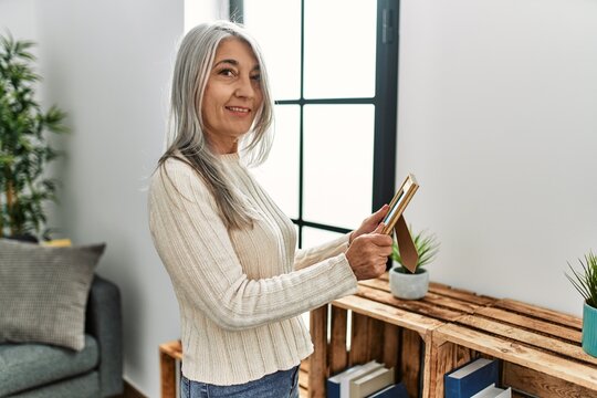 Middle age grey-haired woman smiling confident looking photo at home