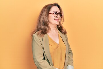 Middle age caucasian woman wearing casual clothes looking away to side with smile on face, natural expression. laughing confident.