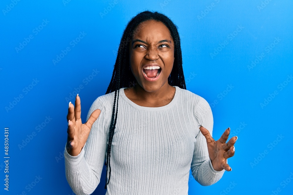 Sticker african american woman with braided hair wearing casual white sweater crazy and mad shouting and yel