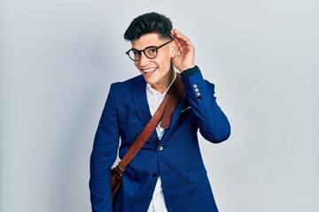 Young hispanic man wearing business clothes smiling with hand over ear listening an hearing to rumor or gossip. deafness concept.