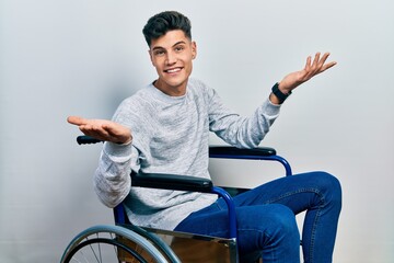 Young hispanic man sitting on wheelchair smiling cheerful with open arms as friendly welcome,...