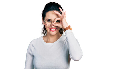 Young hispanic woman wearing casual clothes doing ok gesture with hand smiling, eye looking through fingers with happy face.