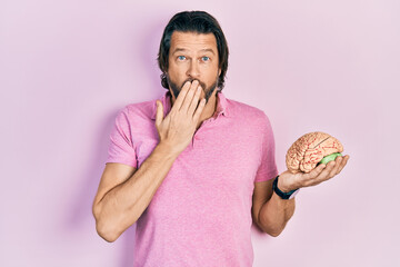 Middle age caucasian man holding brain covering mouth with hand, shocked and afraid for mistake....