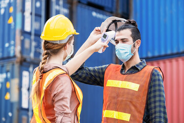 Female engineer worker scanning to check temperature of staff before entering to the container...