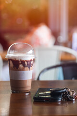 Iced Mocha coffee in plastic mugs that has a phone and key car.