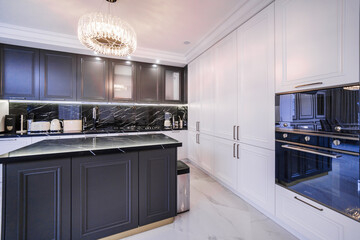 Modern kitchen in a black and white color studio in a studio apartment renovated in contemporary style. A table with a marble top.