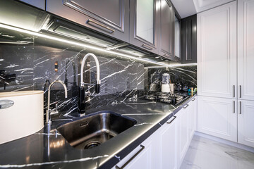 New stylish kitchen with black countertop and white appliances. Black and white cabinet doors