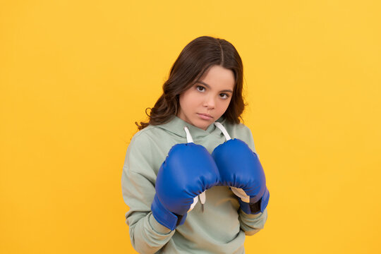 serious child portrait in boxing gloves on yellow background