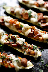 Baked zucchini boats stuffed with vegetarian sausages and cheese, seasoned with fresh herbs, close up view