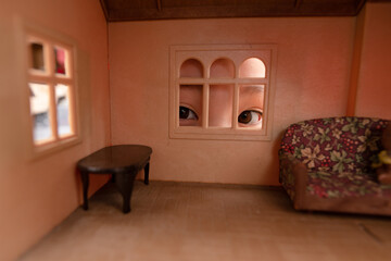 ドールハウスを窓から覗く子供